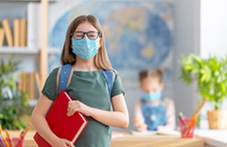 A happy masked student holding a red binder