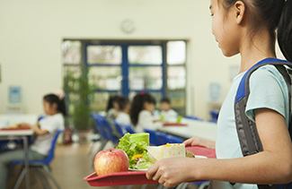 Elementary student holding a school lunch tray in the cafeteria