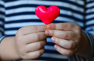 Young student in stripes holding a little red heart