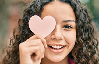 Hispanic girl smiling with a pink heart over one eye