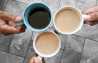 Three staff members holding coffee mugs